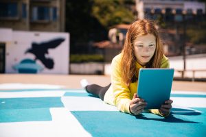 girl on empty playground reading a tablet